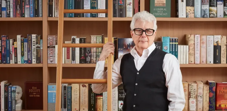 Foto do autor Ken Follett em frente a uma estante de livros