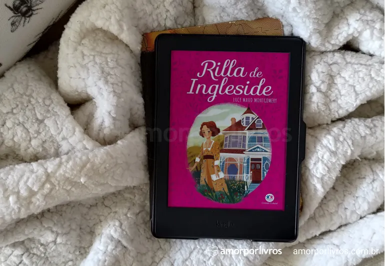 Deitado em uma manta, um kindle com a capa do livro Rilla de Ingleside.